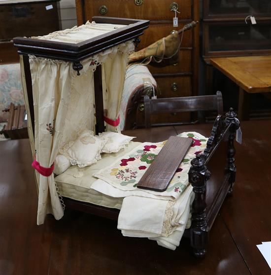A late Victorian dolls half tester bed with 18th century silk curtains, point de gaze pillows and miniature Victorian patchwork